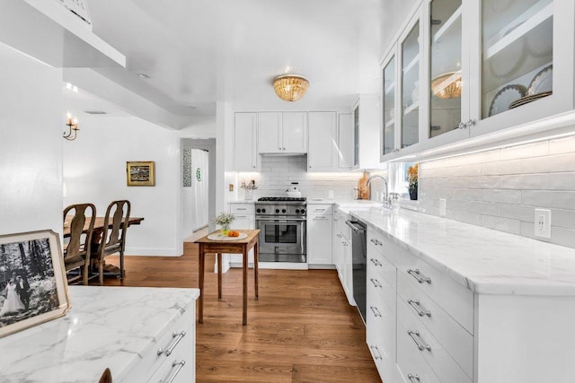 kitchen featuring stainless steel range, light stone countertops, a sink, dishwasher, and decorative backsplash