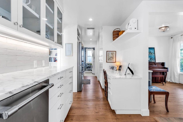 kitchen featuring white cabinets, light stone countertops, dishwasher, dark wood finished floors, and glass insert cabinets