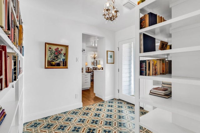 foyer featuring tile patterned flooring, baseboards, an inviting chandelier, and visible vents