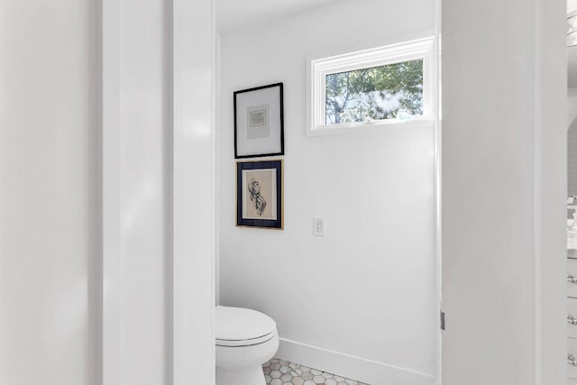 bathroom featuring baseboards, tile patterned flooring, and toilet