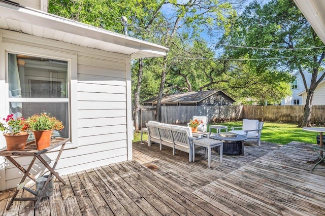 wooden deck featuring a fenced backyard, a lawn, and a fire pit
