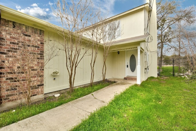 property entrance with fence and a lawn