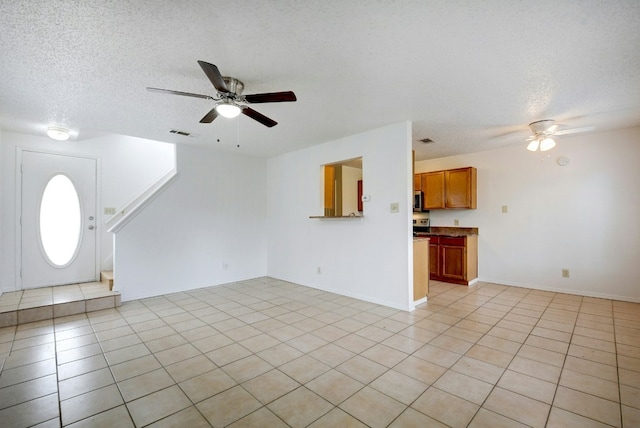 unfurnished living room with visible vents, ceiling fan, light tile patterned flooring, and a textured ceiling