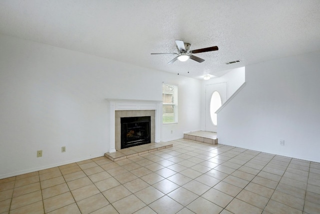 unfurnished living room featuring a fireplace, light tile patterned floors, a textured ceiling, visible vents, and ceiling fan