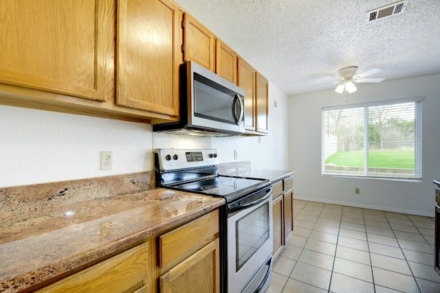 kitchen featuring a textured ceiling, a ceiling fan, visible vents, light tile patterned flooring, and stainless steel appliances