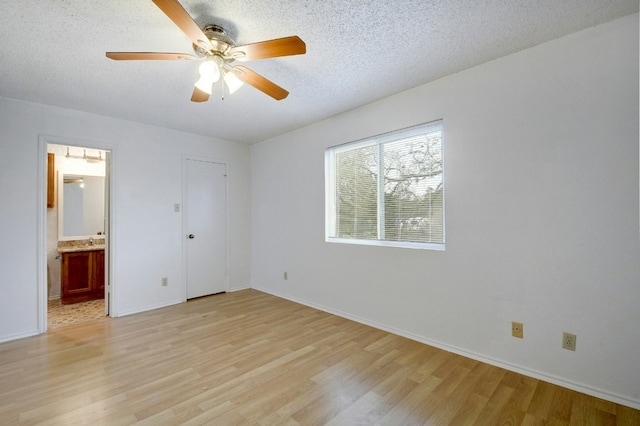 unfurnished bedroom featuring light wood-style flooring, a textured ceiling, and baseboards