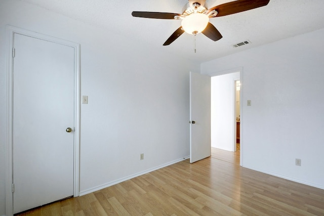 interior space featuring light wood-style flooring, baseboards, a ceiling fan, and visible vents
