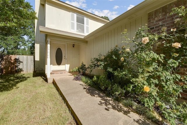 doorway to property featuring fence and a lawn