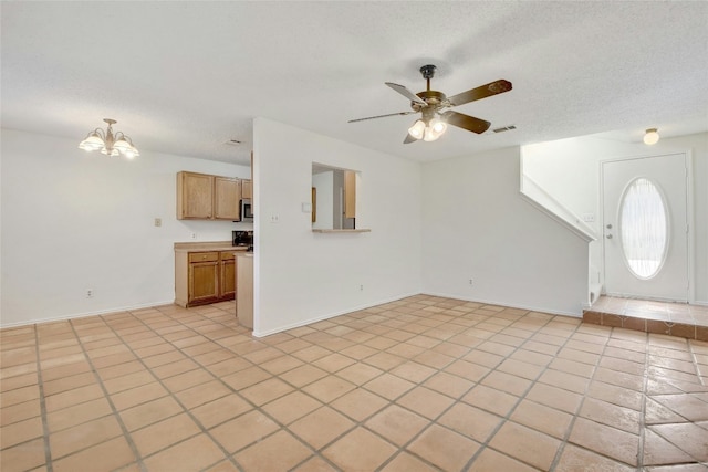 unfurnished living room featuring baseboards, light tile patterned floors, a textured ceiling, visible vents, and ceiling fan with notable chandelier