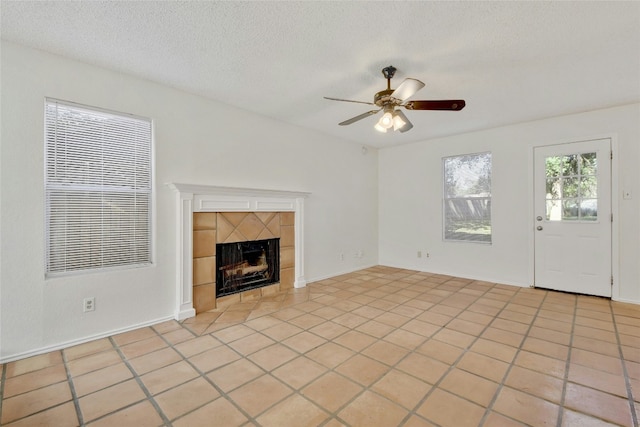 unfurnished living room featuring a textured ceiling, a tiled fireplace, and a ceiling fan