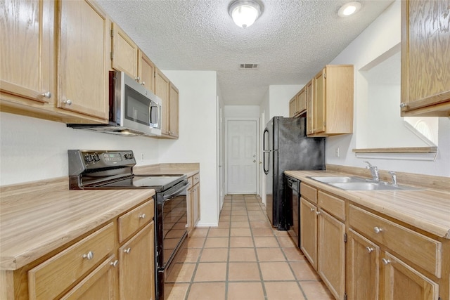kitchen with a sink, light countertops, a textured ceiling, black appliances, and light tile patterned flooring