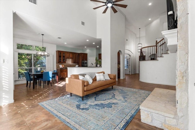 5909 Sunset Rdg, Austin, TX 78735 - living area featuring a ceiling fan, a high ceiling, arched walkways, a chandelier, and stairs
