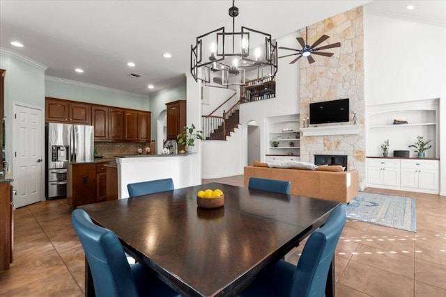 5909 Sunset Rdg, Austin, TX 78735 - dining space with ornamental molding, ceiling fan, a fireplace, stairs, and tile patterned floors