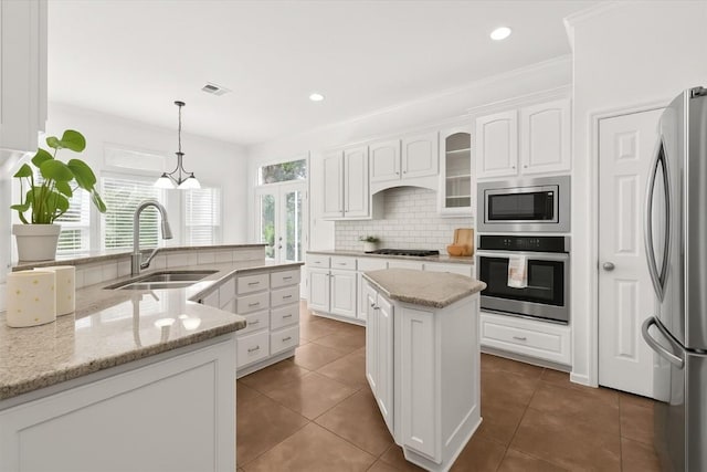 5909 Sunset Rdg, Austin, TX 78735 - kitchen featuring appliances with stainless steel finishes, a sink, a center island, tasteful backsplash, and white cabinets