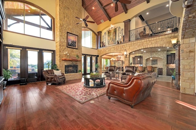 1298 Mystic Pkwy, Spring Branch, TX 78070 - living room featuring high vaulted ceiling, ceiling fan, a wood ceiling with exposed beams, a stone fireplace, and hardwood / wood-style flooring