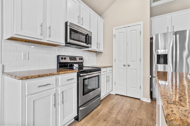 1310 Neuberry Clf, Temple, TX 76502 - kitchen with stainless steel appliances, backsplash, white cabinets, vaulted ceiling, and stone counters