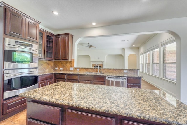 2801 Mirasol Dr, Round Rock, TX 78681 - kitchen with appliances with stainless steel finishes, a sink, a ceiling fan, arched walkways, and light stone countertops