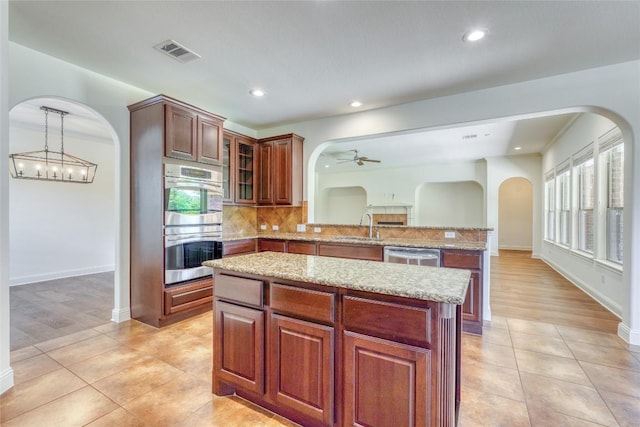 2801 Mirasol Dr, Round Rock, TX 78681 - kitchen featuring arched walkways, stainless steel appliances, a peninsula, a sink, and light tile patterned floors
