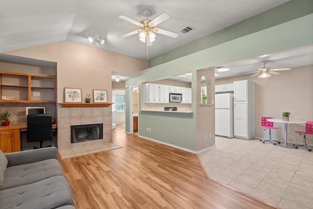 840 Eagles Way, Leander, TX 78641 - living room featuring ceiling fan, vaulted ceiling, light wood-style floors, a desk, and a textured ceiling