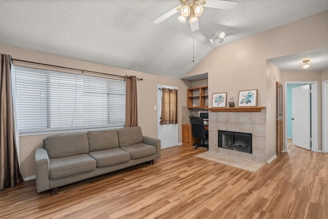 840 Eagles Way, Leander, TX 78641 - living area featuring ceiling fan, light wood-style floors, vaulted ceiling, a textured ceiling, and a tile fireplace