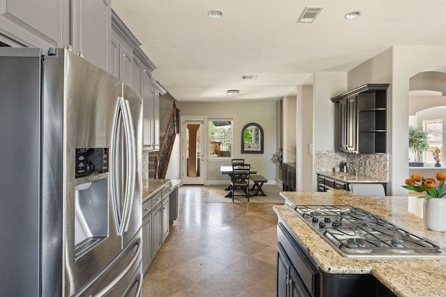 1306 High Lonesome, Leander, TX 78641 - kitchen with stainless steel appliances, open shelves, tasteful backsplash, light stone countertops, and arched walkways