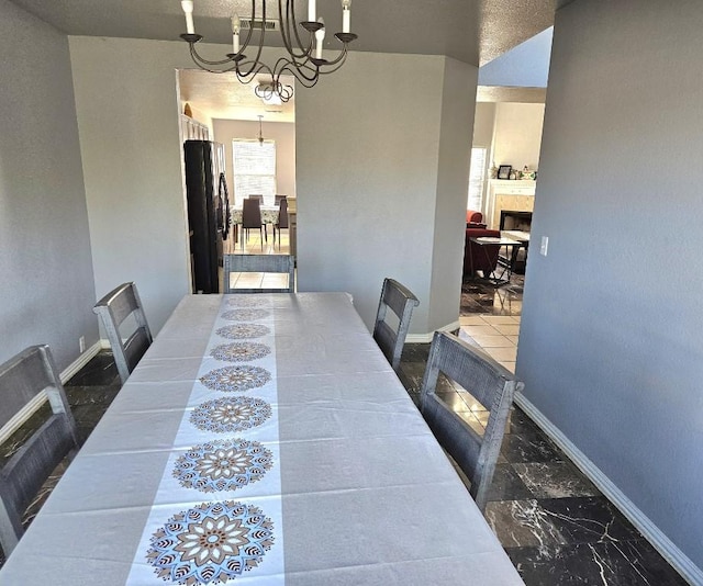 14400 Little Eagle Ct, Elgin, TX 78621 - dining space featuring a chandelier, marble finish floor, baseboards, and a fireplace