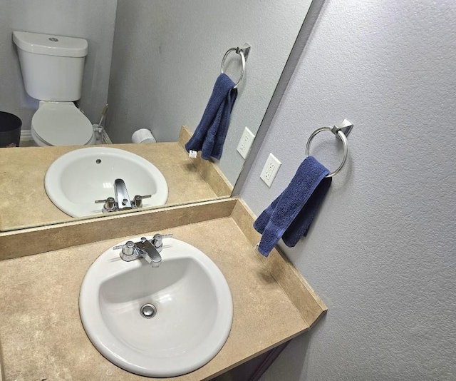 14400 Little Eagle Ct, Elgin, TX 78621 - half bathroom featuring toilet, vanity, and a textured wall
