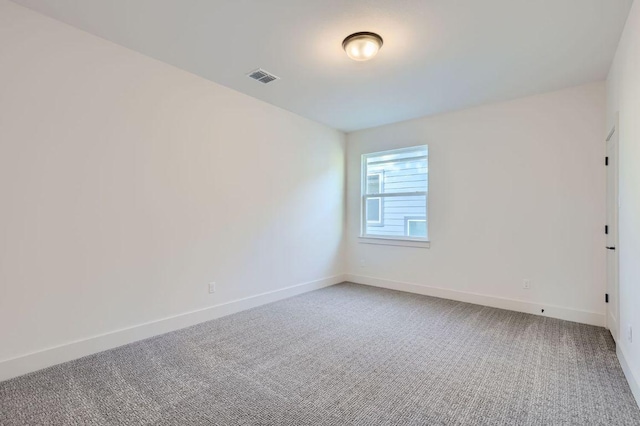 unfurnished room with carpet flooring, visible vents, and baseboards
