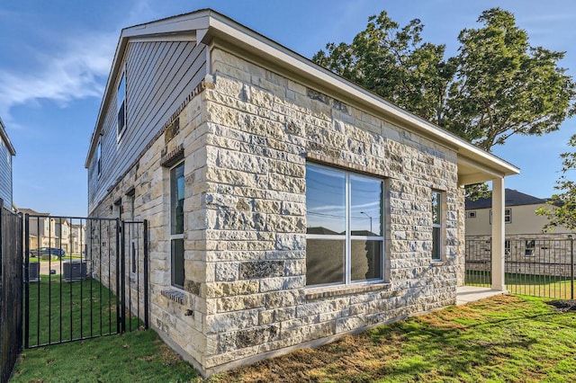 view of property exterior with fence, stone siding, and a lawn
