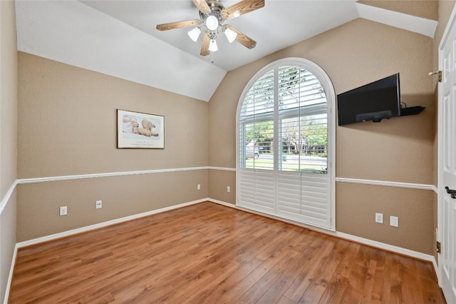 unfurnished room with vaulted ceiling, wood finished floors, baseboards, and ceiling fan