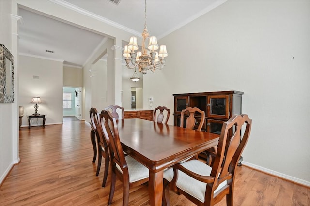 dining room featuring ornamental molding, a chandelier, baseboards, light wood finished floors, and lofted ceiling