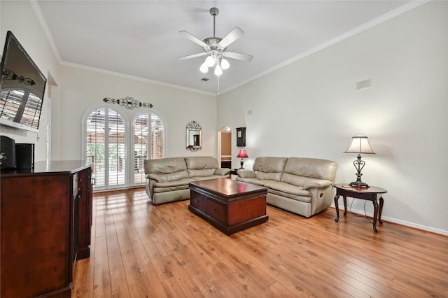living area featuring healthy amount of natural light, light wood-type flooring, arched walkways, ceiling fan, and ornamental molding