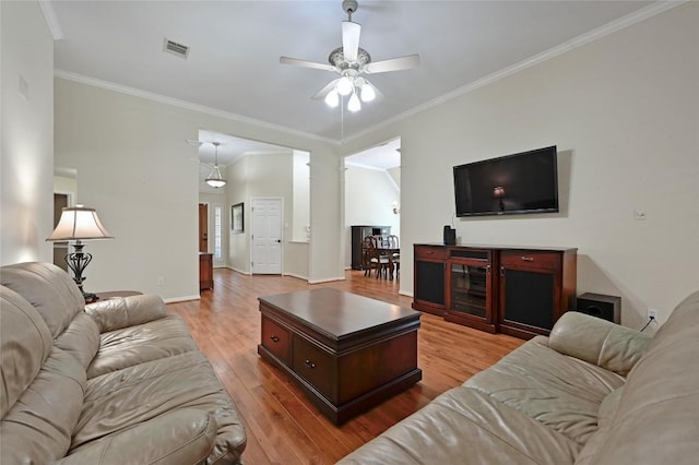 living room featuring a ceiling fan, wood finished floors, crown molding, and baseboards