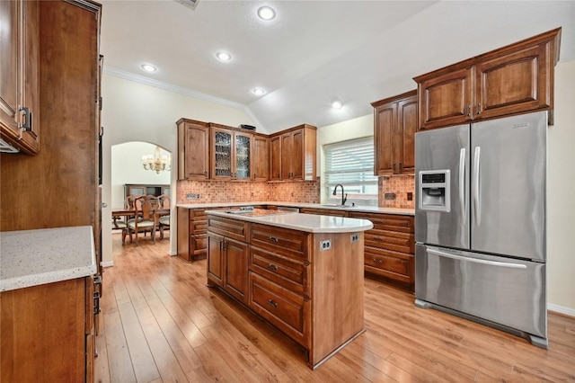 kitchen with stainless steel fridge, a sink, crown molding, light wood-style floors, and tasteful backsplash