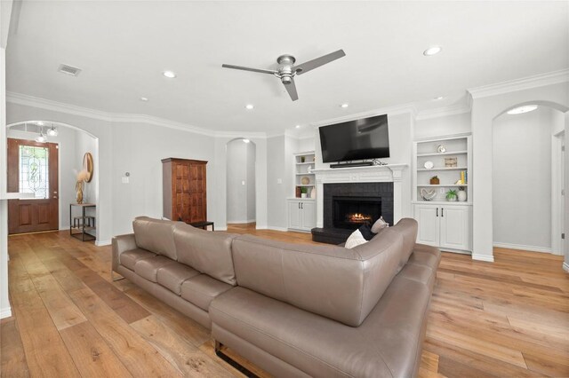 3420 Benecia Ct, Austin, TX 78738 - living area with arched walkways, a ceiling fan, a fireplace, light wood finished floors, and ornamental molding