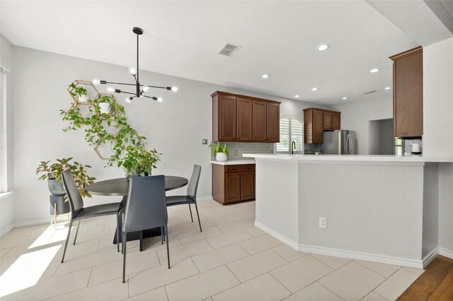 3420 Benecia Ct, Austin, TX 78738 - kitchen with freestanding refrigerator, light countertops, a chandelier, tasteful backsplash, and pendant lighting