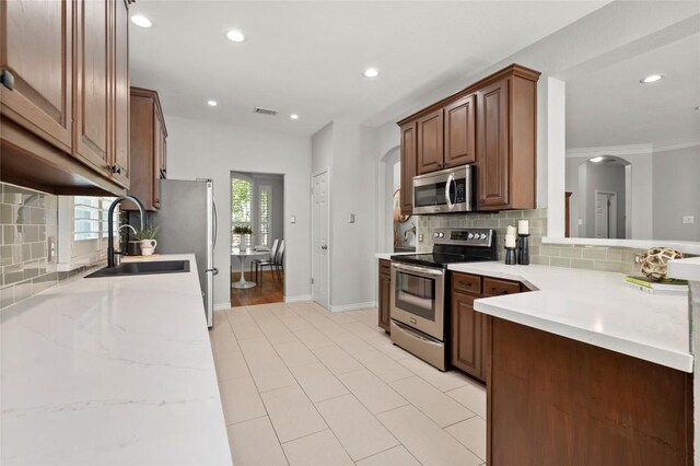 3420 Benecia Ct, Austin, TX 78738 - kitchen with appliances with stainless steel finishes, arched walkways, recessed lighting, tasteful backsplash, and light tile patterned flooring