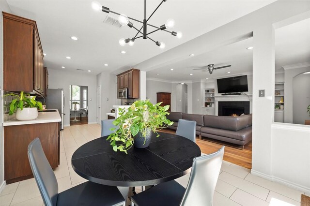 3420 Benecia Ct, Austin, TX 78738 - dining area with a ceiling fan, a lit fireplace, a chandelier, light tile patterned floors, and recessed lighting