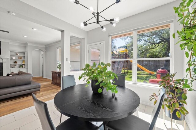 3420 Benecia Ct, Austin, TX 78738 - dining room with a chandelier, arched walkways, built in features, light tile patterned floors, and ornamental molding