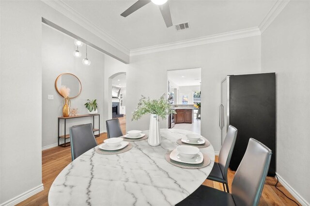 3420 Benecia Ct, Austin, TX 78738 - dining area featuring arched walkways, crown molding, ceiling fan, and light wood-style flooring