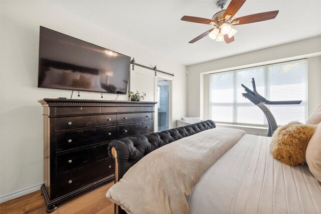 3420 Benecia Ct, Austin, TX 78738 - bedroom with wood finished floors, a barn door, and a ceiling fan