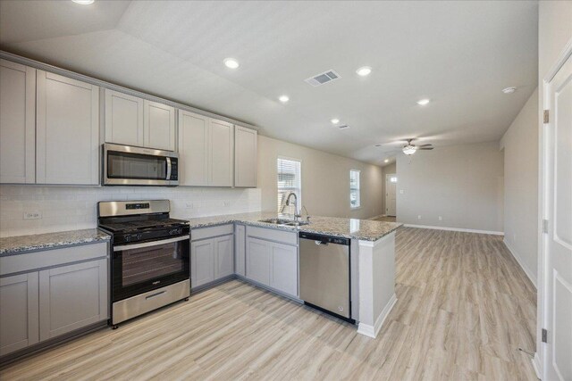 kitchen featuring stainless steel appliances, a sink, gray cabinets, light wood finished floors, and recessed lighting