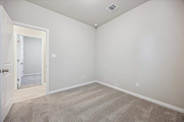 unfurnished room with light carpet, baseboards, and vaulted ceiling