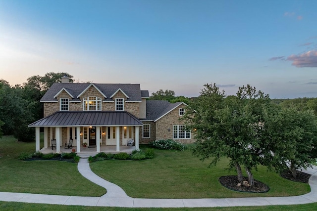 104 Double Cir, Burnet, TX 78611 - view of front of house featuring stone siding, a standing seam roof, a porch, a front lawn, and a chimney