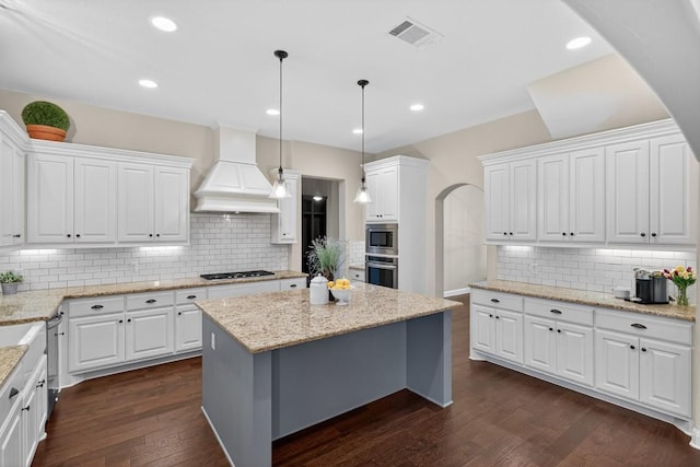 104 Double Cir, Burnet, TX 78611 - kitchen with custom exhaust hood, stainless steel microwave, arched walkways, tasteful backsplash, and white cabinets