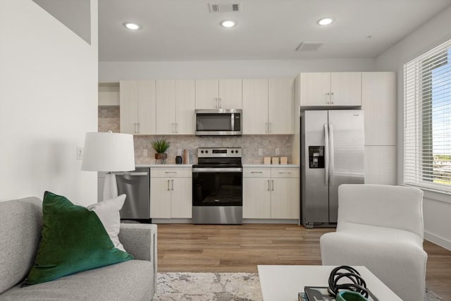 6324 N Lamar Blvd Unit 313, Austin, TX 78752 - kitchen featuring appliances with stainless steel finishes, light wood-type flooring, light countertops, tasteful backsplash, and recessed lighting