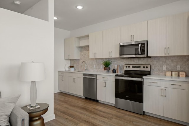 6324 N Lamar Blvd Unit 313, Austin, TX 78752 - kitchen featuring stainless steel appliances, light countertops, backsplash, wood finished floors, and recessed lighting