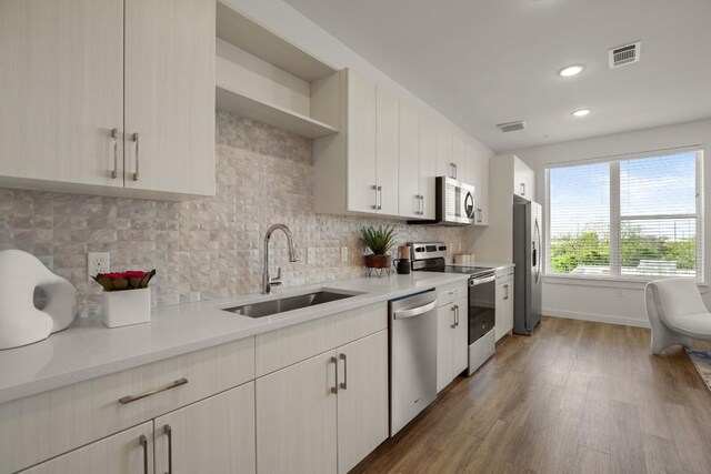 6324 N Lamar Blvd Unit 313, Austin, TX 78752 - kitchen featuring stainless steel appliances, a sink, wood finished floors, light countertops, and recessed lighting