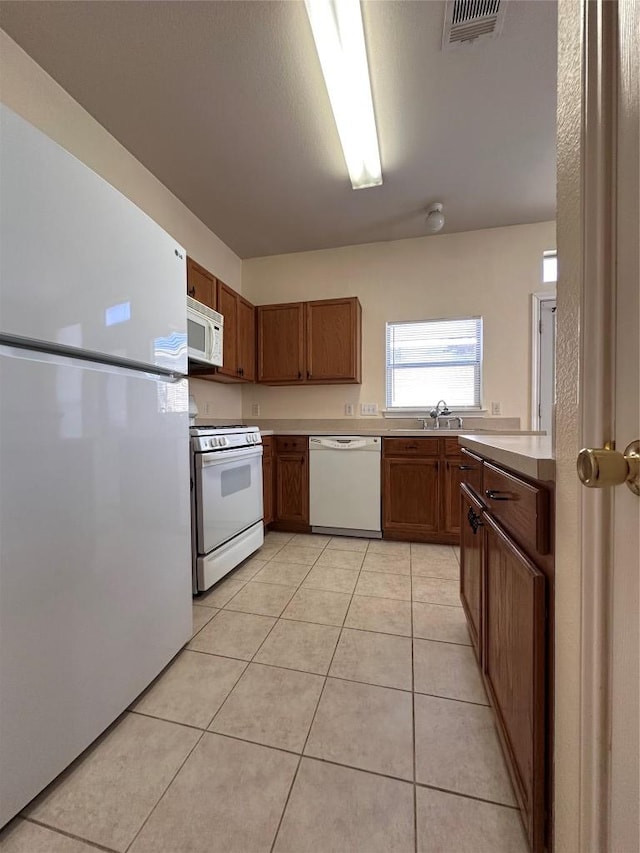 175A Michaelis Unit A, Kyle, TX 78640 - kitchen with white appliances, light countertops, brown cabinets, and light tile patterned floors