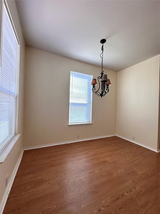 175A Michaelis Unit A, Kyle, TX 78640 - empty room with a chandelier, dark wood-style floors, healthy amount of natural light, and baseboards
